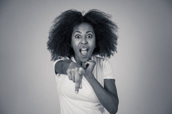 Beautiful shocked african american woman looking and pointing at something unbelievable or having great success with surprised and happy face and gestures. In People and human emotions and expressions.