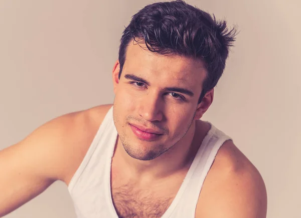 Portrait of young attractive manly latin man in his 20s looking sexy posing against neutral background. Strong fitness model sweet and masculine against neutral background. People and Beauty concept.