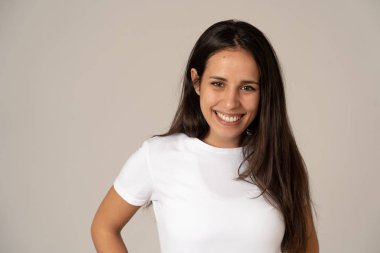 Mutlu yüz güzel gülümseme ve uzun siyah saçlı çekici esmer genç latin kadının yakın portresi. Nötr arka planda izole edilmiş. İnsanlarda, olumlu insan yüz ifadeleri ve duygular.