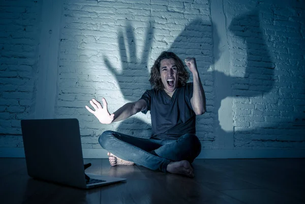 Ciddi dizüstü bilgisayar ile perişan genç genç adam siber zorbalık ve taciz acı online veya dedikodu duygu umutsuz ve siber zorbalık ve sosyal medya aşağılanmış duygu tarafından istismar ediliyor.