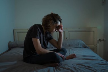 Harap bin yıllık adam üzgün duygu acı ve umutsuz acı Depresyon ağlıyor. Geceleri umutsuzluk içinde yatakta tek başına oturan zorbalık veya istismar depresif genç kurbanı. Genç Ruh sağlığı.