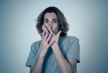 Genç adam korkmuş ve korku ve anksiyete korkmuş jestler yaparak şok hissi. Dehşete düşmüş çaresiz bir genç kendini saldırganlıktan korumaya çalışıyor. Halk ifadeleri ve gençlik şiddeti.