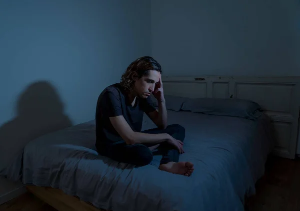 Devastated millennial man crying sad feeling hurt and hopeless suffering Depression. Depressed teenager victim of bullying or abuse sitting on bed alone in despair at night. In teenage Mental health.