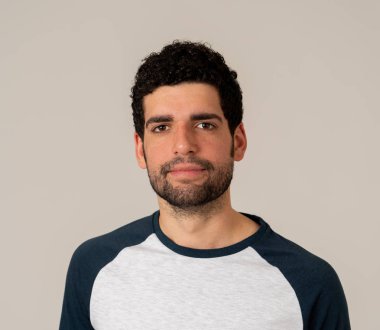 Sakallı ve koyu saçlı doğal ve nötr yüz ifadesi ile genç latin adam yakın headshot. Nötr arka planda izole edilmiş. İnsanlar moda, Lifestyle Güzellik ve İnsan duyguları.