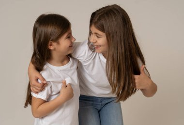 Birlikte sarılma ve kamera için poz gülerek eğlenen iki neşeli kardeş kız kız kardeşlerin Sevimli portre. Stüdyo kopya alanı ile vurdu. Aile ve çocuklarda mutlu anlar birlikte.