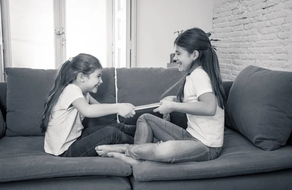 Younger and older girls fighting for laptop arguing over playing on the internet. Lifestyle portrait of sisters not sharing computer in Relationship between siblings and technology addiction concept.