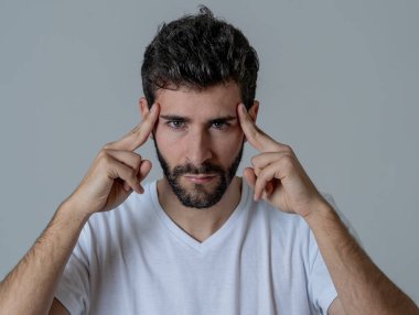 Büyük acı içinde migren muzdarip endişeli ve düşünceli görünümlü genç bir adamın yakın portresi. Nötr arka planda izole edilmiş. Yüz ifadeleri ve duygular ve sağlık bakım kavramı.
