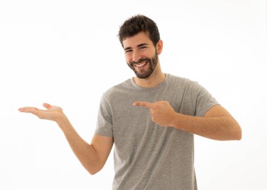 İyi görünümlü genç adam kopya alanı işaret eden neşeli mutlu ve heyecanlı görünümlü. Sakallı hipster metin reklam içeriği için boş arka plan üzerinde izole ilginç bir şey gösteren.