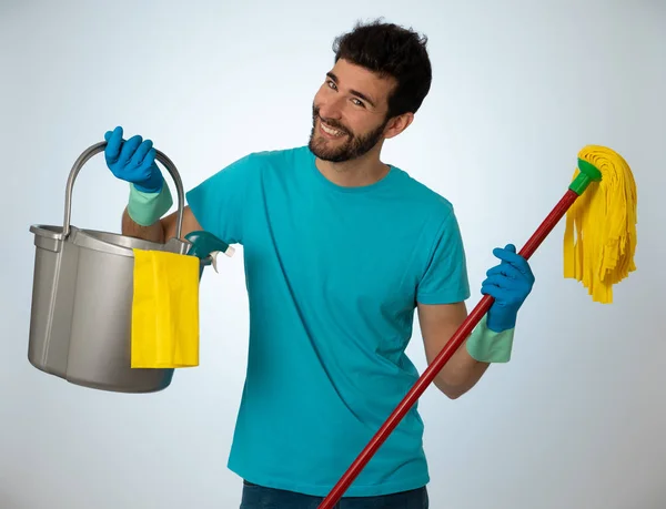 Breaking gender stereotypes. Portrait of attractive happy man proud holding cleaning equipment ready to do housework. isolated on blue background. In changing men and women roles in society.