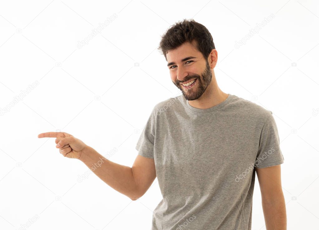 Good looking young man pointing finger at copy space looking cheerful happy and excited. Bearded hipster showing something interesting isolated on empty background for text advertising content.