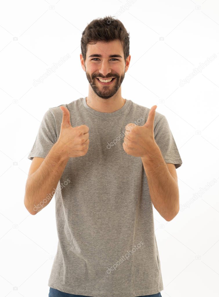 Portrait of good looking young man showing thumbs up sign feeling cheerful, happy and satisfied. Young happy student male making thumb up in joyful approval gesture isolated on white background.
