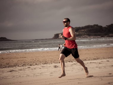 Gün batımında sahilde yalınayak koşan atlet koşucu. Spor adam fitness modeli açık fitness eğitimi, spor, motivasyon ve aktif sağlıklı yaşam tarzı kavramı deniz kıyısında çalışma.