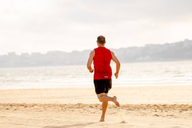 Gün batımında sahilde yalınayak koşan atlet koşucu. Spor adam fitness modeli açık fitness eğitimi, spor, motivasyon ve aktif sağlıklı yaşam tarzı kavramı deniz kıyısında çalışma.