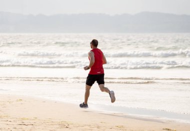 Atlet koşucu adam koşu, sprint ve spor eğitimi gün batımında plajda giymek. Spor ve Aktif sağlıklı yaşam tarzı nda fitness modeli erkek eğitim ve deniz kıyısında açık havada çalışma.