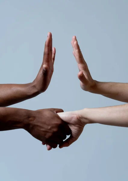 Black African American and Caucasian hands holding together. Conceptual image of Races coming together in world unity and stop racism. In racial tolerance understanding and cooperation concept