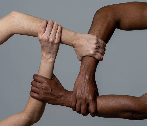 Races united against discrimination and racism. Black African American and Caucasian hands holding together in world unity and racial love and understanding. Tolerance and cooperation concept.