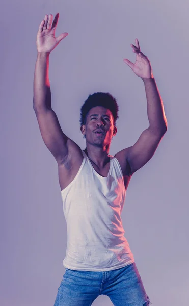 Portrait of inspired cool african american teenager man dancing feeling the music and enjoying life on blue moody disco neon light background. In People, Youth Party night lifestyle. Studio shot.