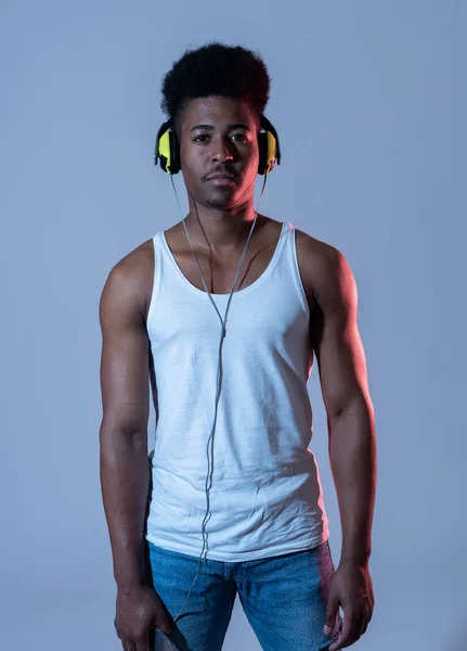 Artistic portrait of strong african american young dancer or DJ with headphones ready to play or dance in disco dance floor neon light in Internet Music festival and online music technology concept.