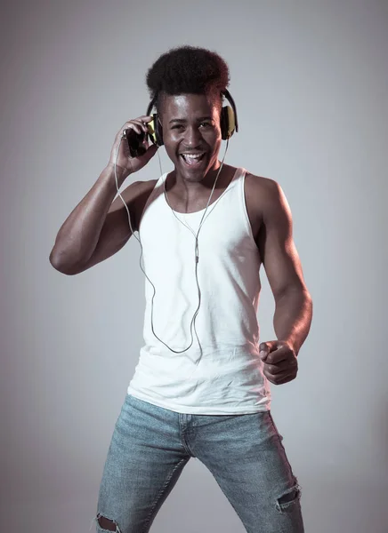 Strong african american young dancer man listening to music online dancing and singing with headphones. Artistic portrait with disco dance floor neon light in Internet Music and technology concept.