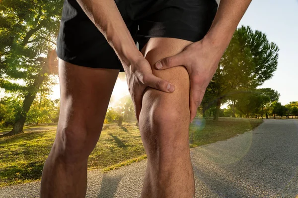 年轻的适合男子抱着膝盖与手在痛苦后遭受肌肉损伤打破膝盖疼痛扭伤或抽筋在户外跑步 在身体疼痛和运动训练损伤和身体保健 — 图库照片