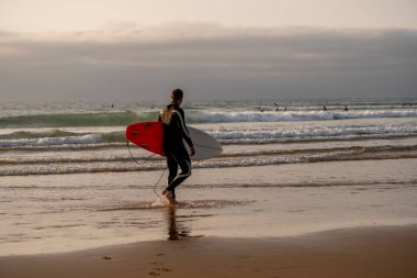 Gün batımında veya gün doğumunda sörf sörf sörf ile çekici sörfçü. Ekstrem sporlar, açık hava su sporları, sörf tatil ve macera yaşam tarzı kavramı.