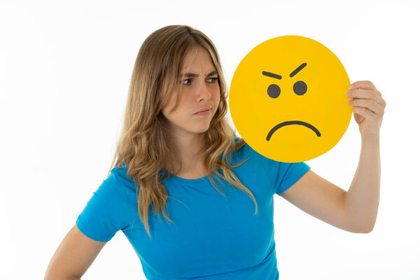 Привлекательная молодая женщина, держащая в руках смайлик смайлика злого лица, изолированный на белом фоне в выражениях лица, взаимодействиях в социальных сетях, иконах уведомлений в социальных сетях и коммуникациях
.