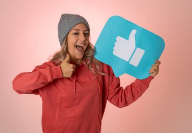 Elinde sembolik sosyal medya bildirim ikonu gibi bir şey tutan güzel genç bir kadın takipçilerden online yorumlarını, blogunu veya işini sevmelerini istiyor. İnternet saplantısı, ağ kurma ve teknoloji bağlantılarında.