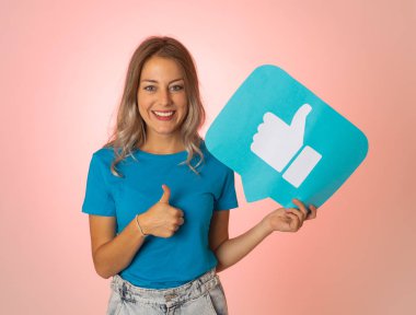 Elinde sembolik sosyal medya bildirim ikonu gibi bir şey tutan güzel genç bir kadın takipçilerden online yorumlarını, blogunu veya işini sevmelerini istiyor. İnternet saplantısı, ağ kurma ve teknoloji bağlantılarında.