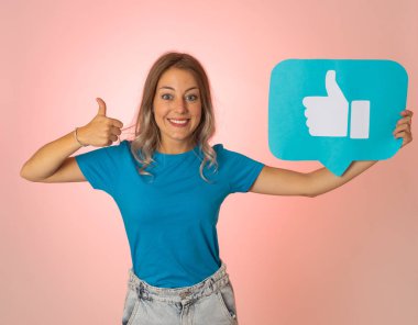 Elinde sembolik sosyal medya bildirim ikonu gibi bir şey tutan güzel genç bir kadın takipçilerden online yorumlarını, blogunu veya işini sevmelerini istiyor. İnternet saplantısı, ağ kurma ve teknoloji bağlantılarında.