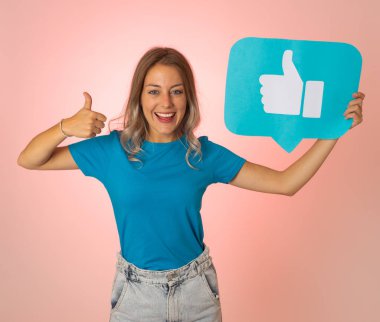 Elinde sembolik sosyal medya bildirim ikonu gibi bir şey tutan güzel genç bir kadın takipçilerden online yorumlarını, blogunu veya işini sevmelerini istiyor. İnternet saplantısı, ağ kurma ve teknoloji bağlantılarında.