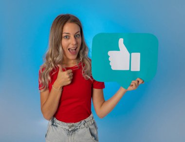 Elinde sembolik sosyal medya bildirim ikonu gibi bir şey tutan güzel genç bir kadın takipçilerden online yorumlarını, blogunu veya işini sevmelerini istiyor. İnternet saplantısı, ağ kurma ve teknoloji bağlantılarında.
