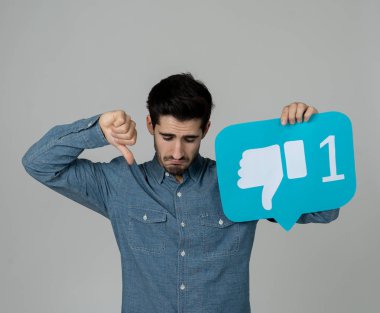 Sosyal medyada mutsuz olmanın ve internet takıntısının, sosyal ağ bilgilendirme ikonlarının, siber zorbalığın ve teknoloji iletişiminin reddedilmesinin sosyal medya sembolünü elinde tutan çekici mutsuz genç adam..