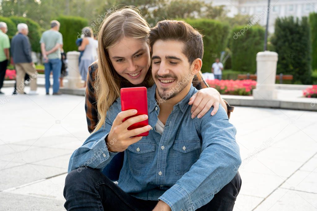 Young couple on social media using smart phone app to post and comment in blog online. Young man and woman looking online inluencers and sharing photos in social network with family and friends.