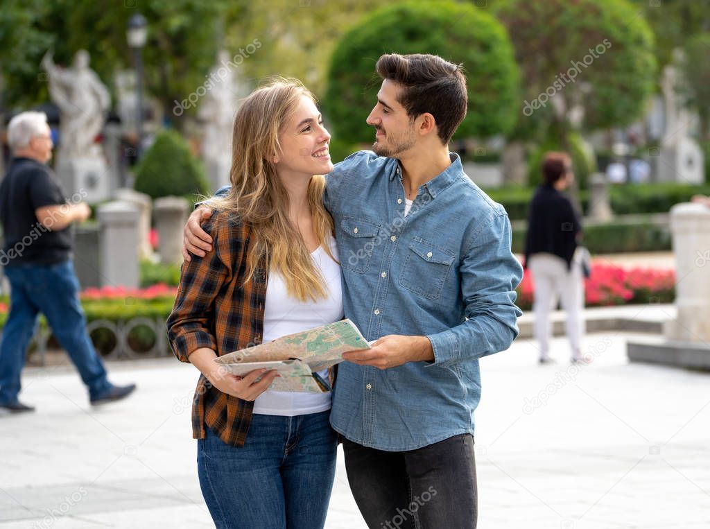 Holidays, dating, city break and tourism concept. Happy young friends tourists couple reading a map and visiting main landmarks while traveling around Europe. Outdoors european city urban background.