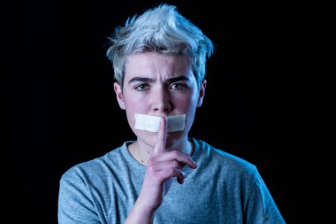 Sansür ve sosyal tabunun kavramsal görüntüsü. Ağzı bantla mühürlenmiş transseksüel genç bir adam. Sessiz bir jest yapıyor. İletişim kuramıyor ya da kendi cinsiyetini ifade edemiyor..