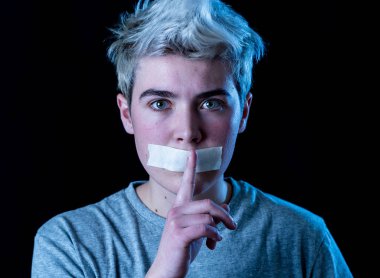 Sansür ve sosyal tabunun kavramsal görüntüsü. Ağzı bantla mühürlenmiş transseksüel genç bir adam. Sessiz bir jest yapıyor. İletişim kuramıyor ya da kendi cinsiyetini ifade edemiyor..