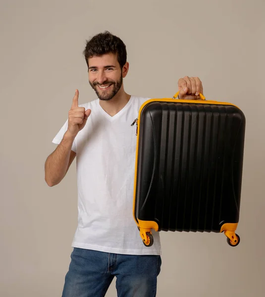 Attractive young traveler man showing suitcase isolated on neutral background. Advertising style image for storage space for travelers, tourism and travel vacation concept.