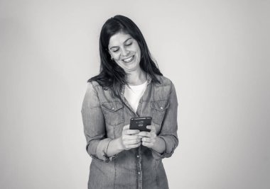 Akıllı telefondan sohbet eden ve sosyal medya uygulamalarını gri arka planda izole ederek mesajlaşan oldukça mutlu bir kadın. İnsanlarda, yaşam tarzında, çevrimiçi iş ve teknoloji kullanımında.