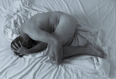 Genç, çaresiz, çıplak bir adam yatakta yalnız başına ağlıyor. Yıkılmış ve reddedilmiş hissediyor. Erkeklerde zihinsel sağlık sorunlarının kavramsal imajı, depresyon, intihar ve uyuşturucu bağımlılığı.
