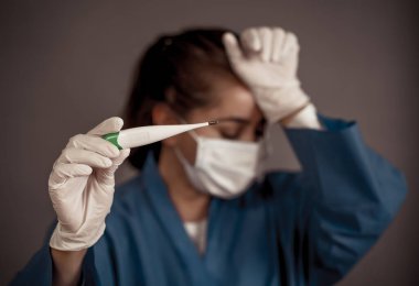 COVID-19 Salgın görsel destek. Doktor termometreyi tutuyor. Kendini koru ve koronavirüsün yayılmasını engelle. Ateşiniz, öksürüğünüz ve nefes almakta güçlük çekiyorsanız, tıbbi yardım isteyin..
