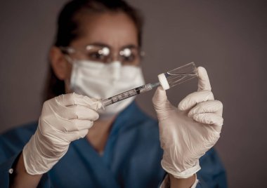 COVID-19 Coronavirus aşısı. Sars-CoV-2 virüsünü inceleyen şırıngalı bir bilim adamı aşı araştırması için klinik deneylere hazır. Kadın araştırmacı laboratuarda potansiyel aşıyı test ediyor..