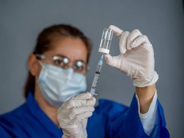 COVID-19 Coronavirus aşısı. Sars-CoV-2 virüsünü inceleyen şırıngalı bir bilim adamı aşı araştırması için klinik deneylere hazır. Kadın araştırmacı laboratuarda potansiyel aşıyı test ediyor..
