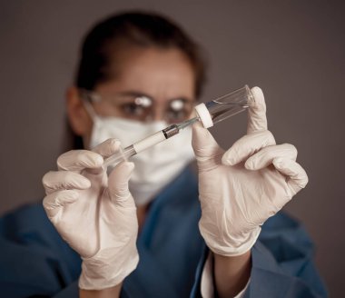 COVID-19 Coronavirus aşısı. Sars-CoV-2 virüsünü inceleyen şırıngalı bir bilim adamı aşı araştırması için klinik deneylere hazır. Kadın araştırmacı laboratuarda potansiyel aşıyı test ediyor..