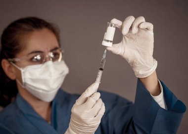 COVID-19 Coronavirus aşısı. Sars-CoV-2 virüsünü inceleyen şırıngalı bir bilim adamı aşı araştırması için klinik deneylere hazır. Kadın araştırmacı laboratuarda potansiyel aşıyı test ediyor..
