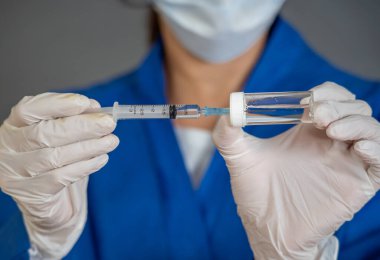 COVID-19 Coronavirus aşısı. Sars-CoV-2 virüsünü inceleyen şırıngalı bir bilim adamı aşı araştırması için klinik deneylere hazır. Kadın araştırmacı laboratuarda potansiyel aşıyı test ediyor..
