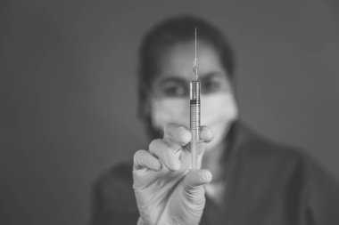 COVID-19 Coronavirus aşısı. Sars-CoV-2 virüsünü inceleyen şırıngalı bir bilim adamı aşı araştırması için klinik deneylere hazır. Kadın araştırmacı laboratuarda potansiyel aşıyı test ediyor..