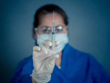 COVID-19 Coronavirus aşısı. Sars-CoV-2 virüsünü inceleyen şırıngalı bir bilim adamı aşı araştırması için klinik deneylere hazır. Kadın araştırmacı laboratuarda potansiyel aşıyı test ediyor..