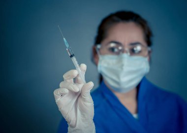 COVID-19 Coronavirus aşısı. Sars-CoV-2 virüsünü inceleyen şırıngalı bir bilim adamı aşı araştırması için klinik deneylere hazır. Kadın araştırmacı laboratuarda potansiyel aşıyı test ediyor..