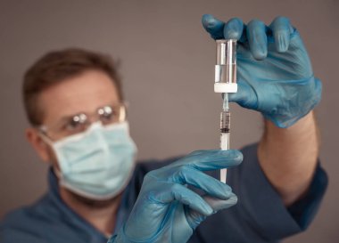 COVID-19 Coronavirus aşısı. Sars-CoV-2 virüsünü inceleyen şırıngalı bir bilim adamı aşı araştırması için klinik deneylere hazır. Erkek araştırmacı laboratuvarda potansiyel aşıyı test ediyor..