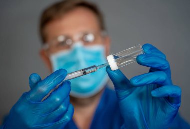 COVID-19 Coronavirus aşısı. Sars-CoV-2 virüsünü inceleyen şırıngalı bir bilim adamı aşı araştırması için klinik deneylere hazır. Erkek araştırmacı laboratuvarda potansiyel aşıyı test ediyor..
